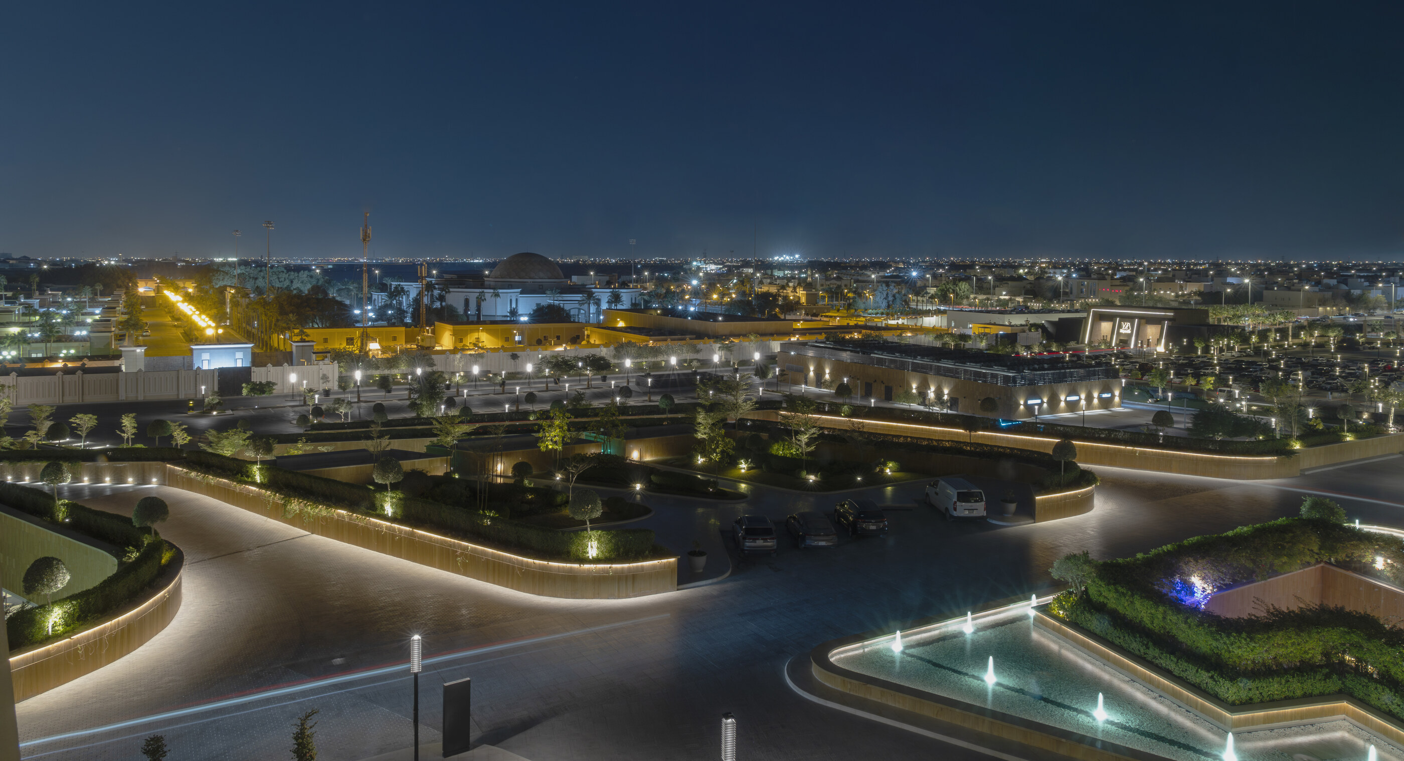 A dusk view of an Indian city — pools, a long colonnade, lights starting to come on. The wide travel-essay shot of India at dusk; place as protagonist.