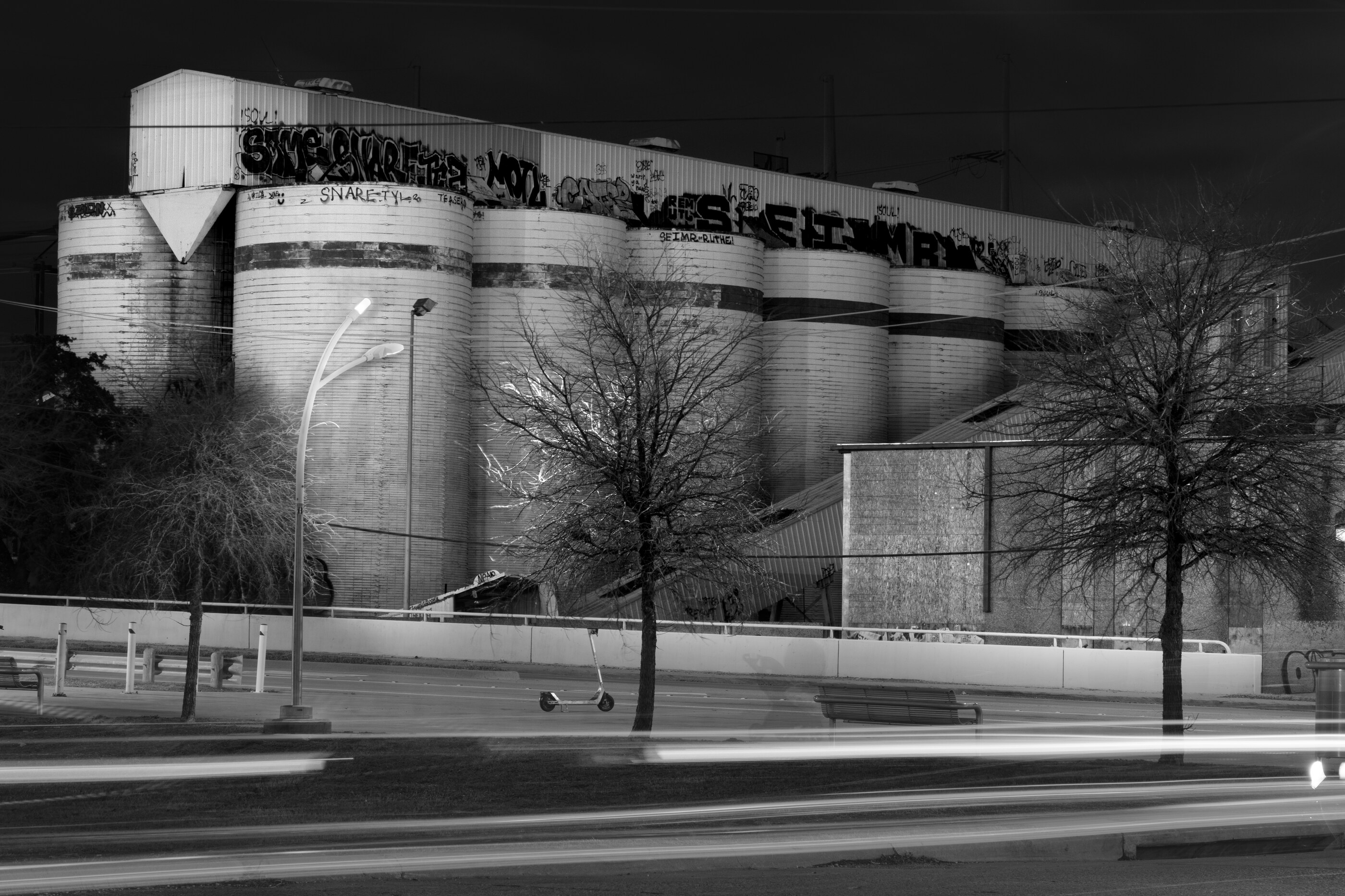 A dark, monochromatic industrial building with strong geometric facade, photographed straight on. No people. The built form — the factory itself — is the subject of the photograph.