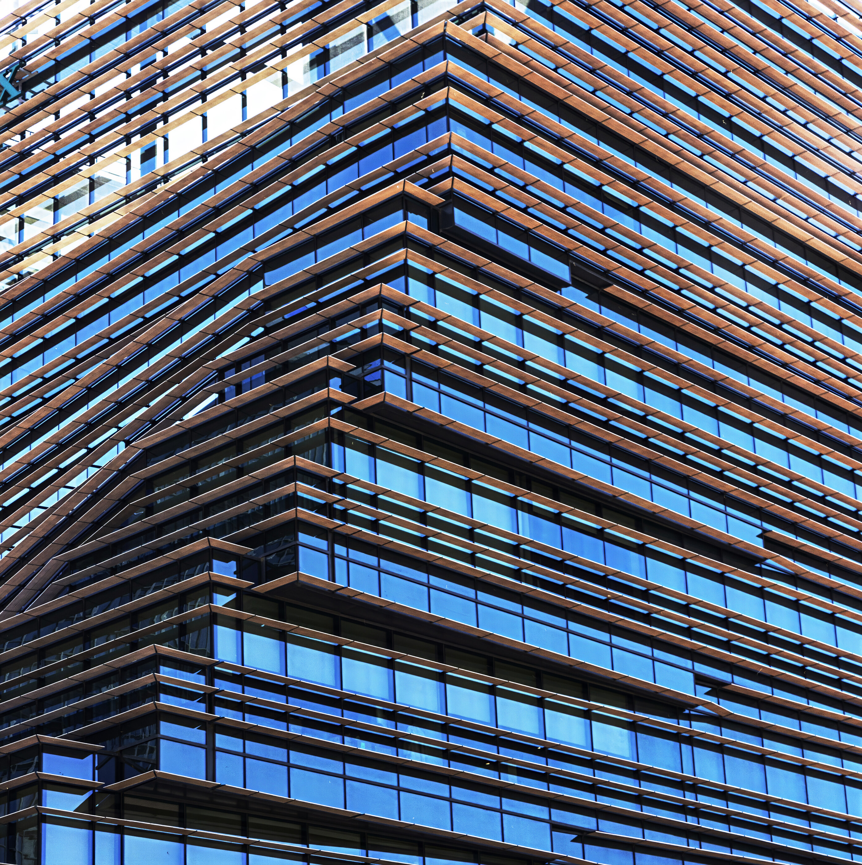 A modern building with grids of dark glass and bright accents. No people are visible. Geometric repetition of the curtain wall is the subject.