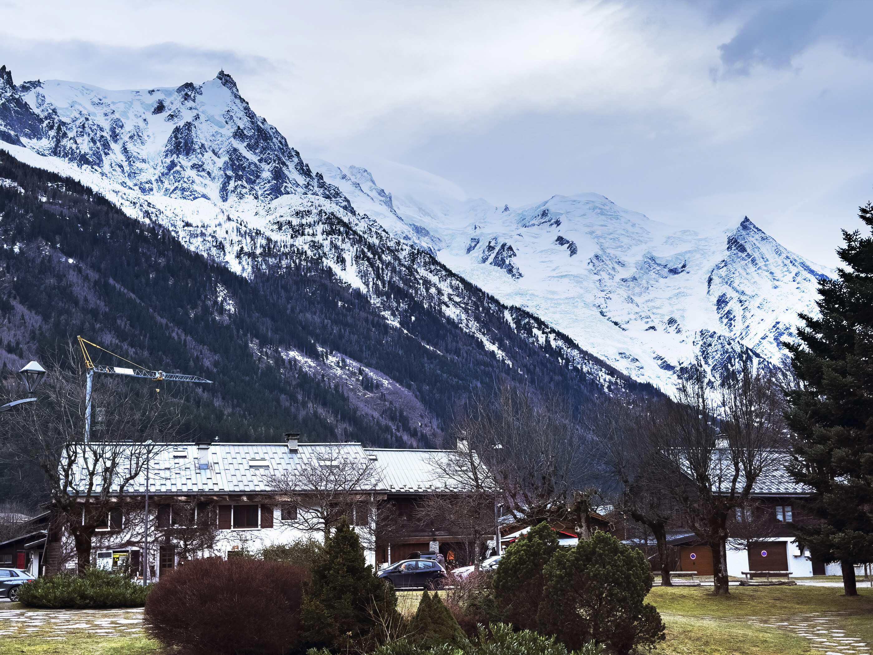 Snowy mountains rising behind a few small chalet-style buildings in the foreground. The land dominates the frame; the buildings are scale markers. No athletic activity.