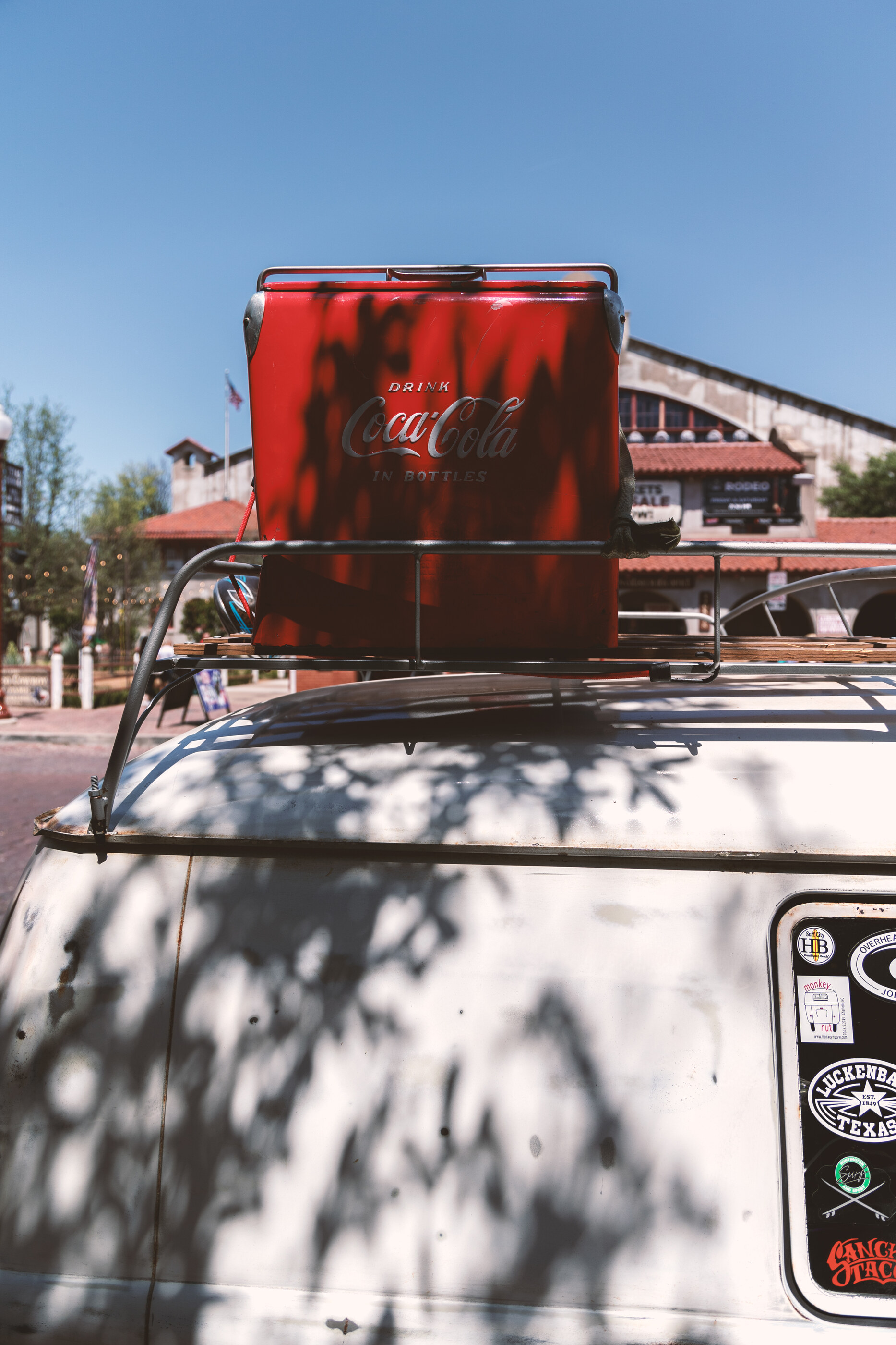 A red Coca-Cola cooler box or truck panel against a peeled-paint backdrop, weathered. No people. The object — its colour, branding, and wear — is the subject.