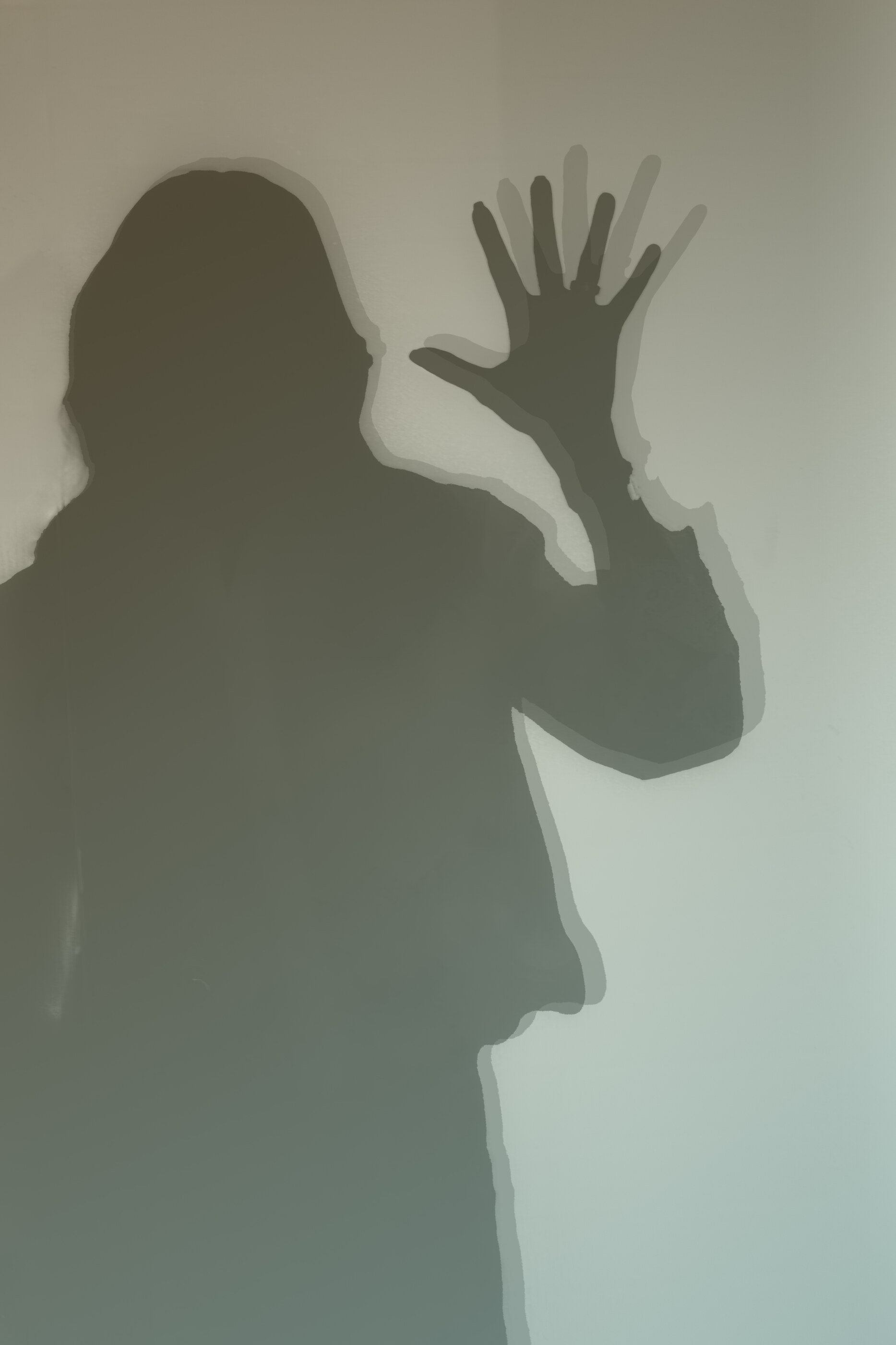 A black-and-white silhouette of a figure's hand and outline pressed against frosted glass, only the dark shape visible.