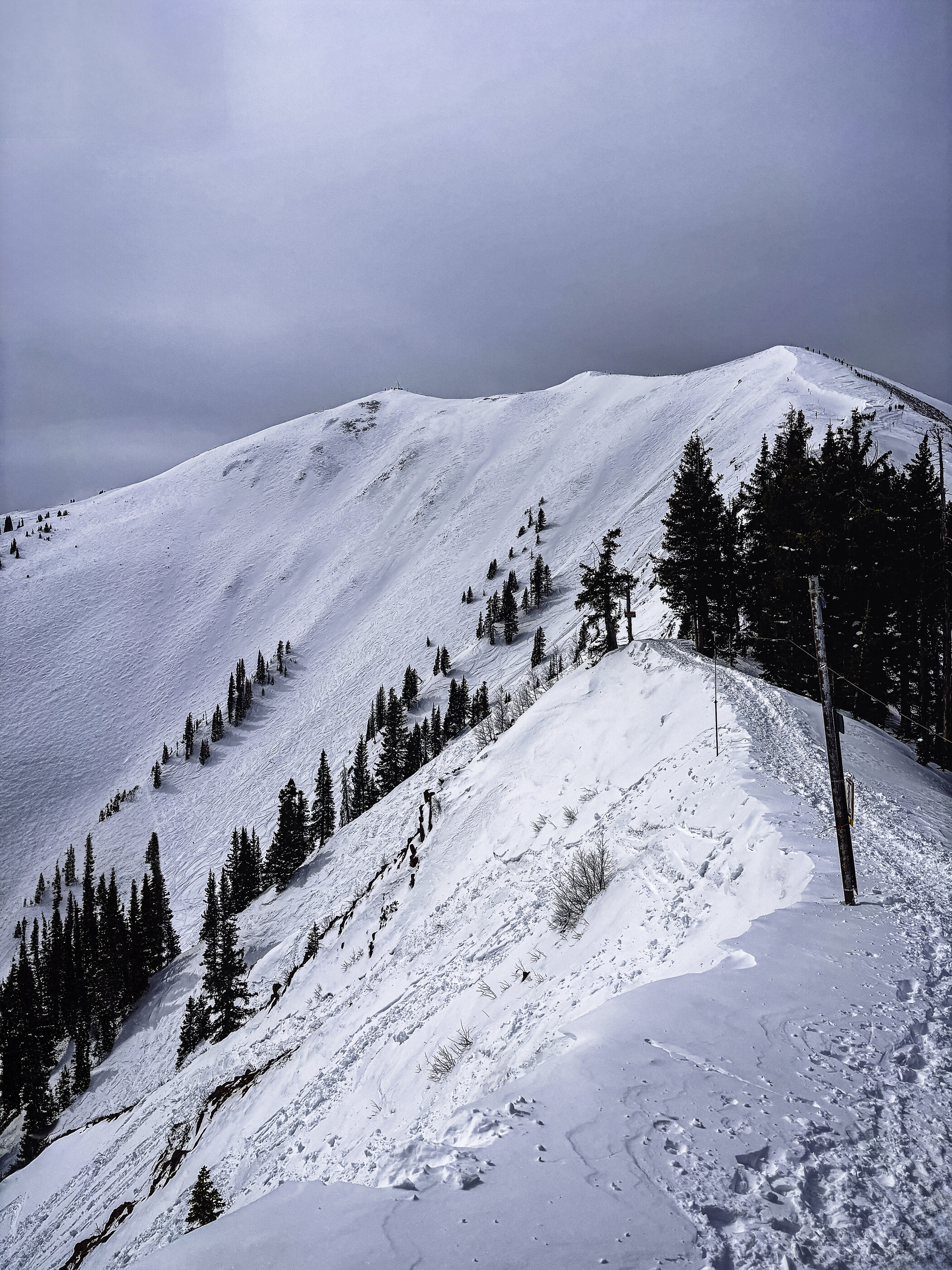A snow-capped mountain peak with dramatic clouds rolling over the ridge. There are no people in the frame and no athletic activity. The land at scale is the unambiguous subject.