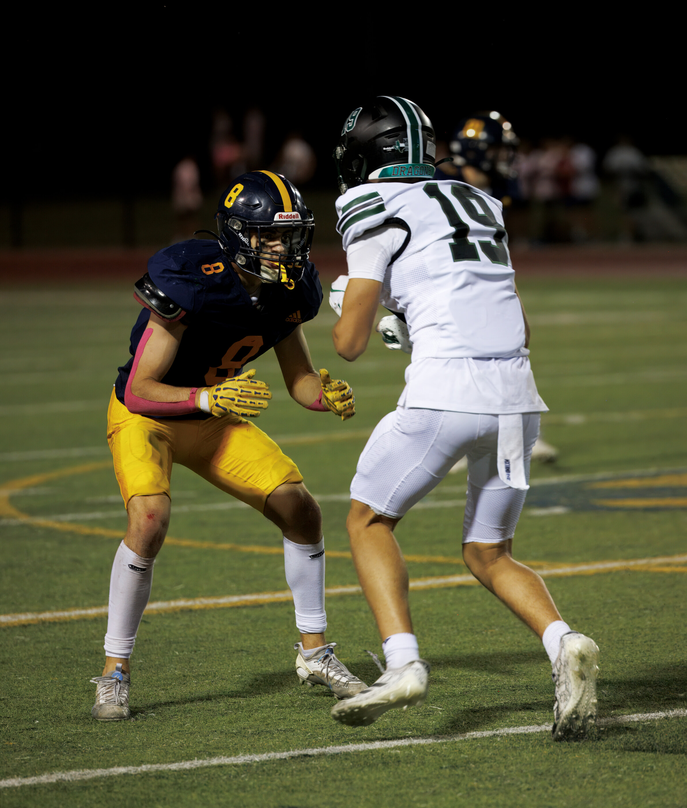 A close shot of two football players in collision or block, mid-game intensity. Athletic action.