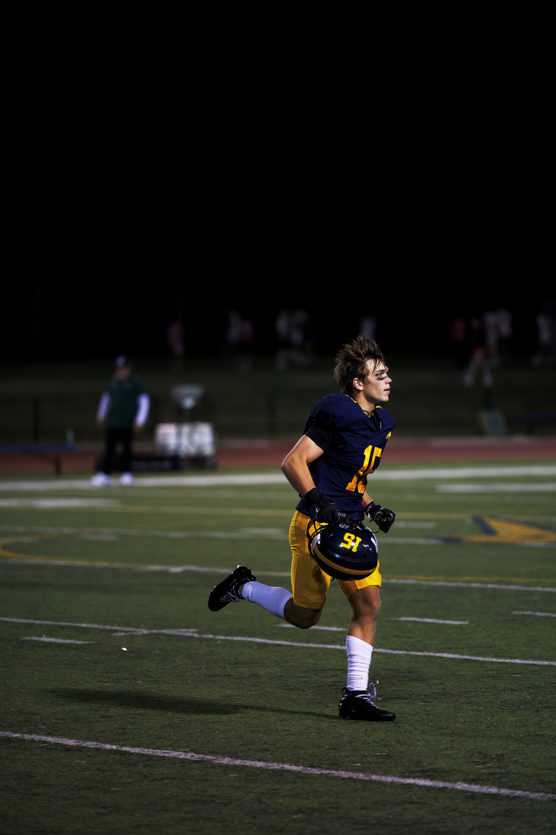 A football player running across the field, focused expression. Athletic action is the subject.