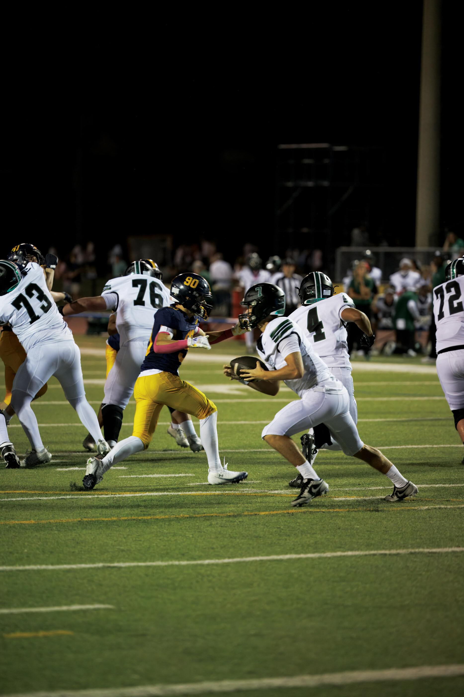 Multiple football players in mid-play formation, helmets and pads visible. Game action is the subject.