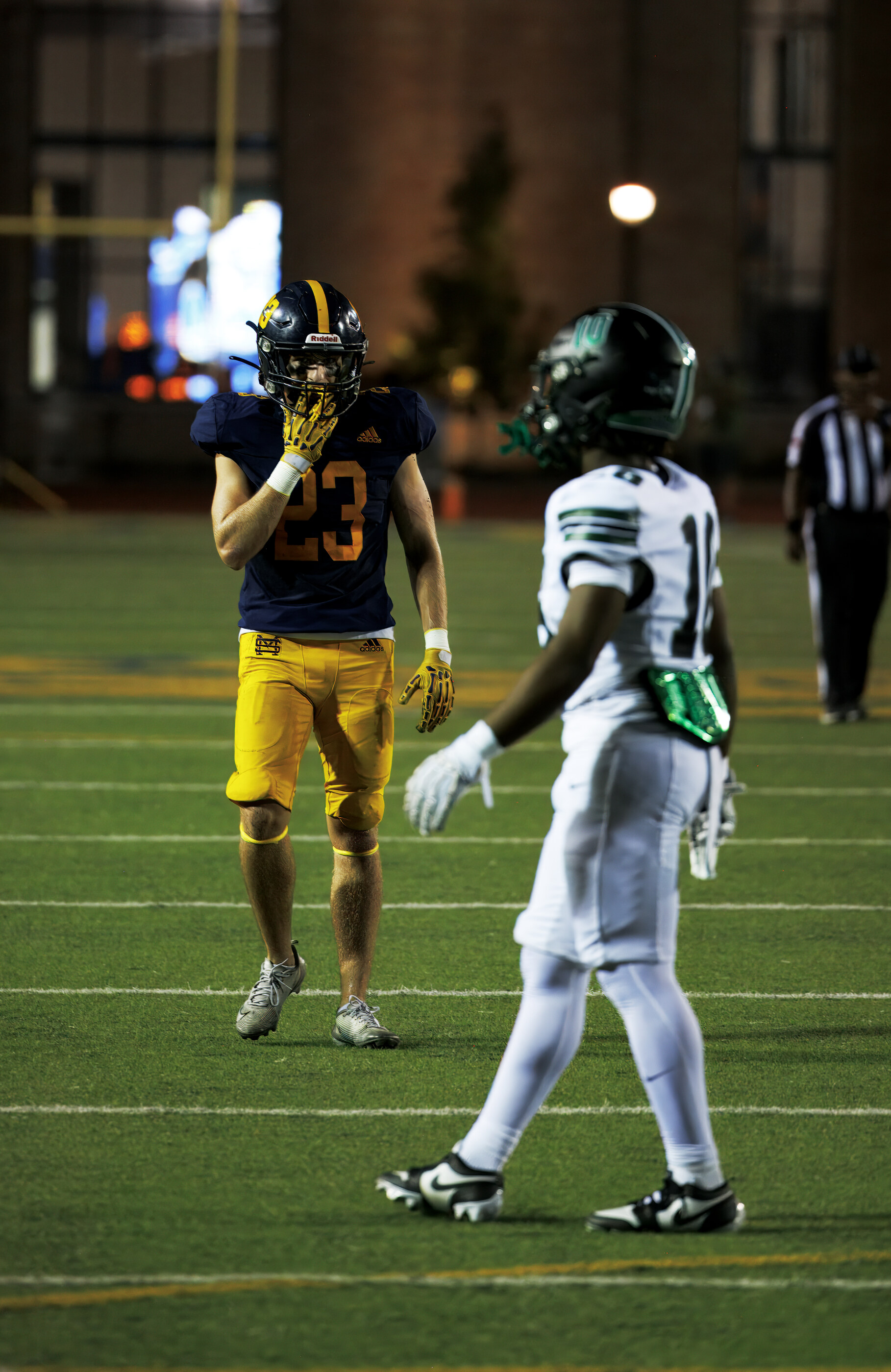 Two football players in defensive stance facing off across the line. Athletic context and game uniforms.