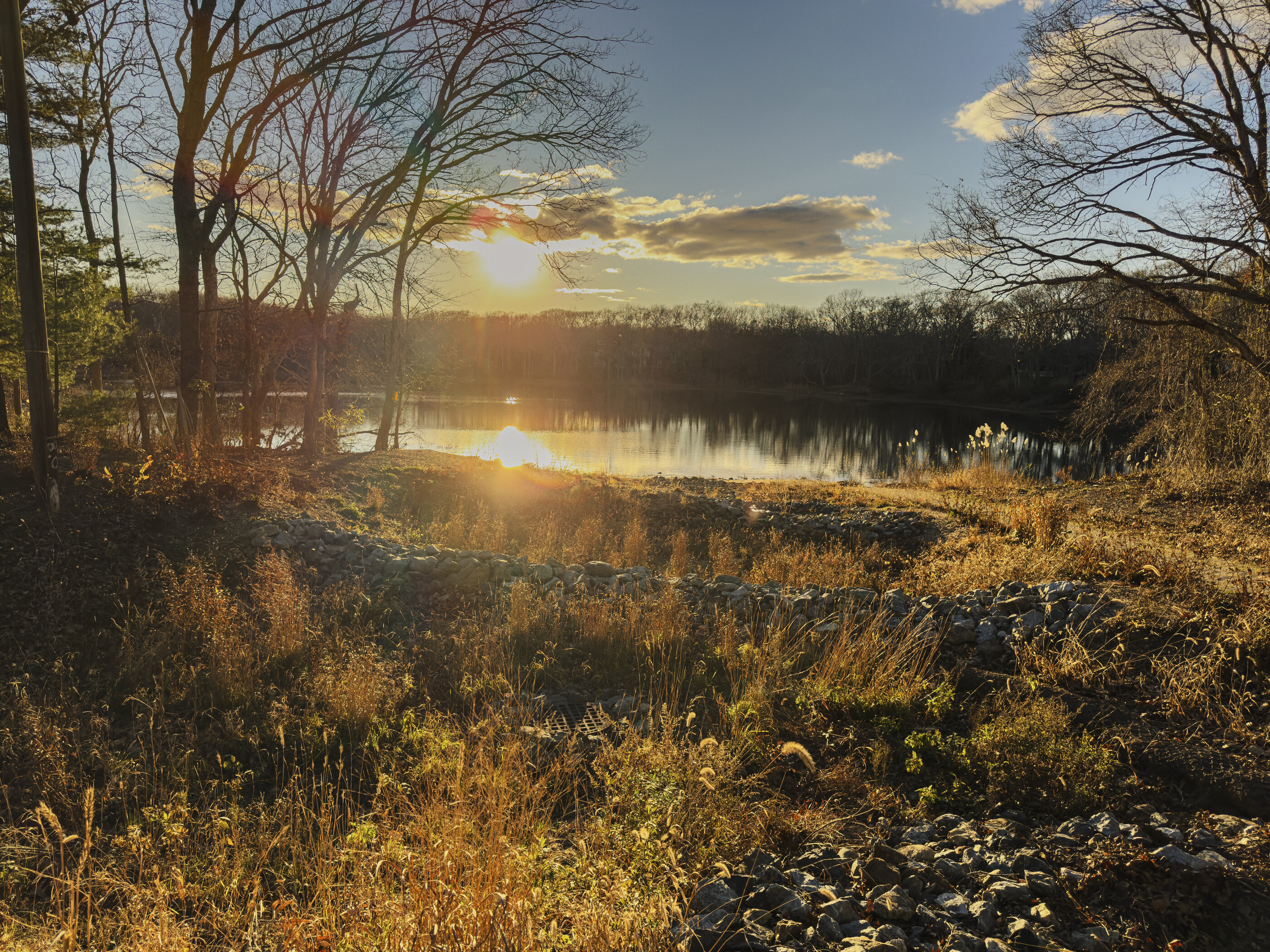 A still lake with autumn forest on the far shore and a mountain rising behind, late golden light. No people. Quiet, slow, contemplative — closer to a stillness photograph than a vast place.
