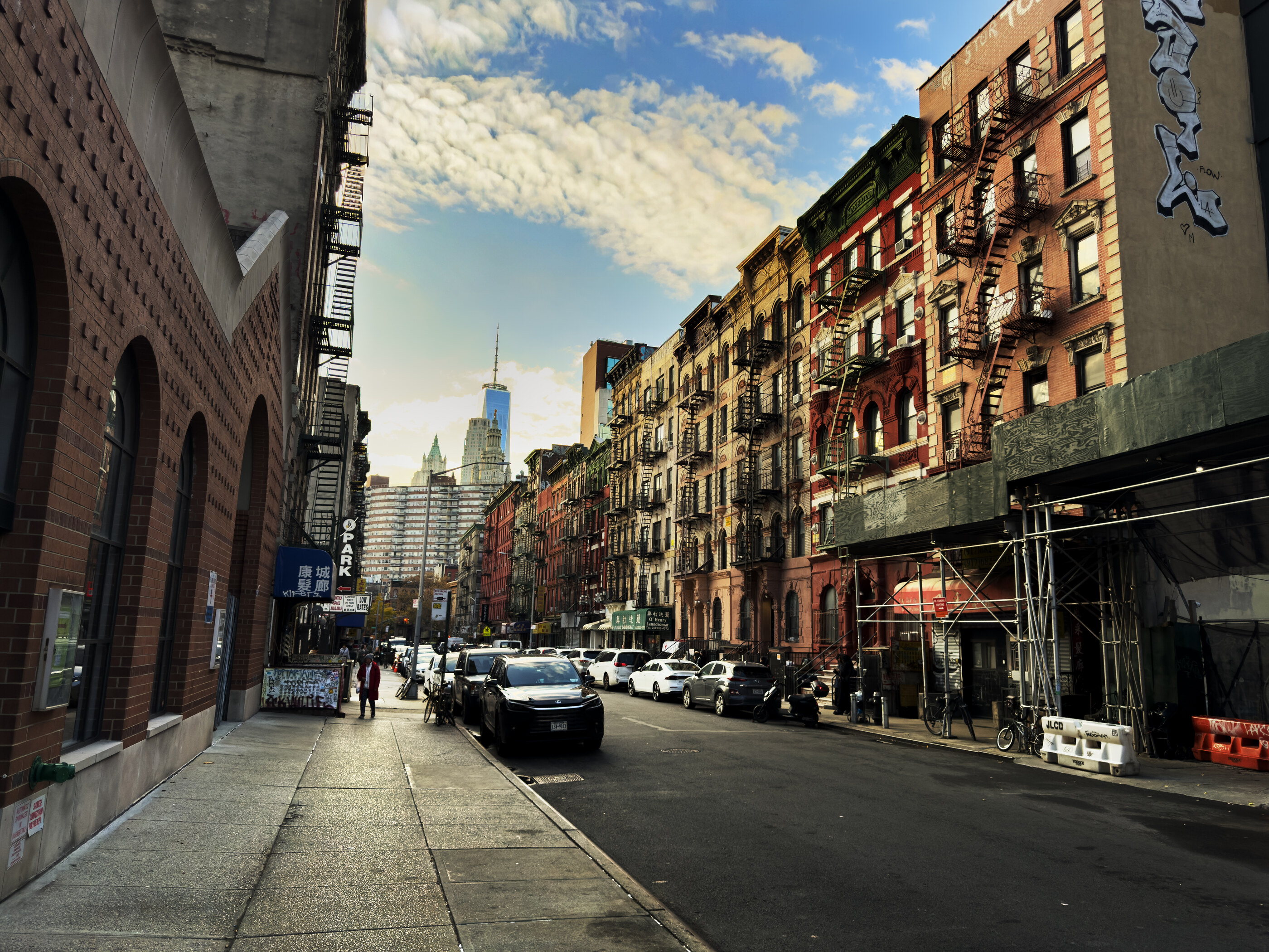 A cobblestone street in Tribeca, New York, with two cars parked along a row of cast-iron and brick warehouses.